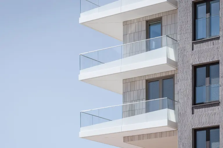 Fachada del hotel realizada con ladrillos verticales, además de balcones con antepechos de vidrio estampado