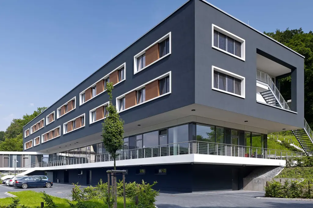 Vista exterior de un edificio escolar con fachada oscura, aislamiento de EPS y revestimiento de acab